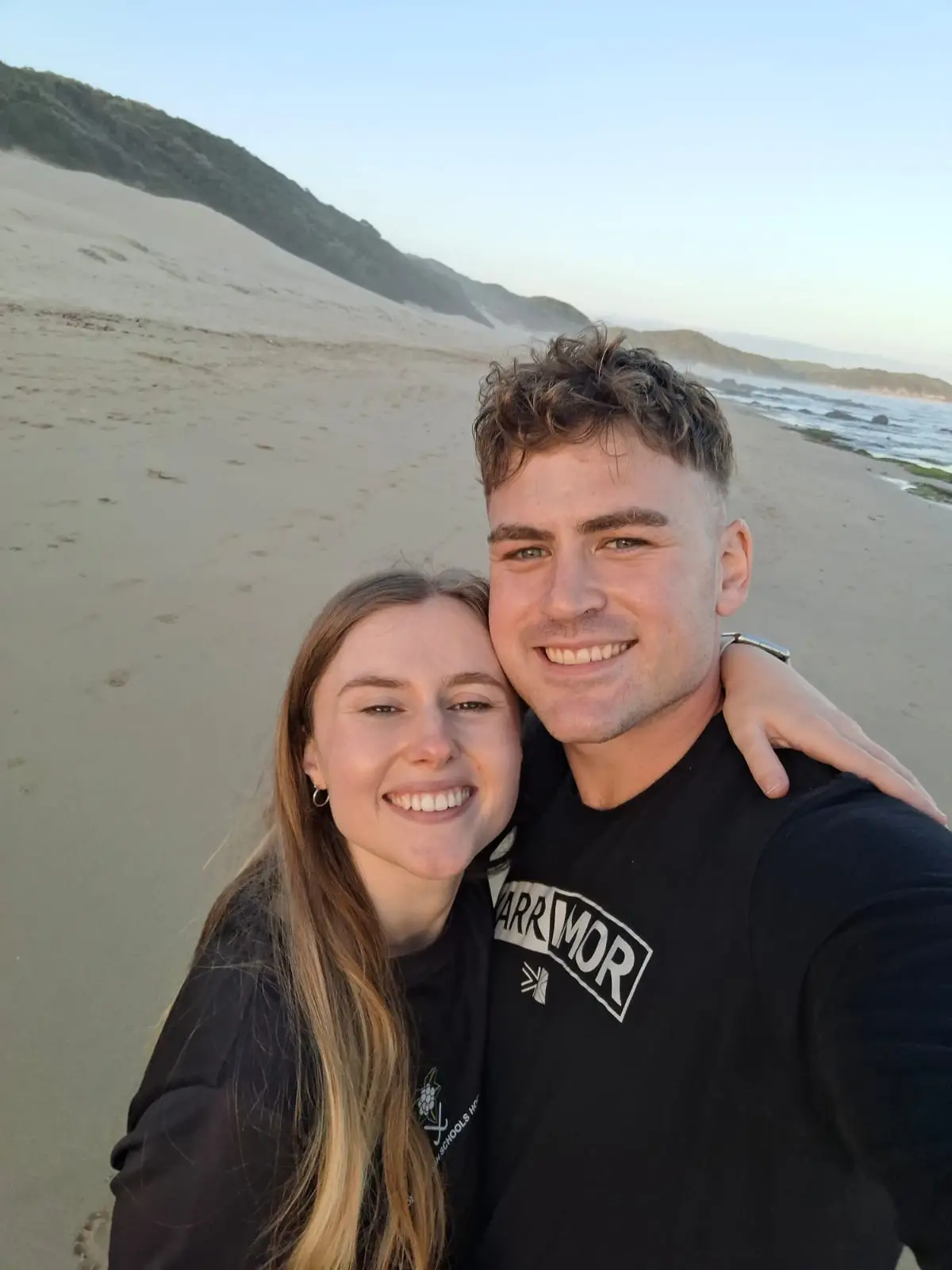 Ockert en Emja op die strand, met duine agter hulle.