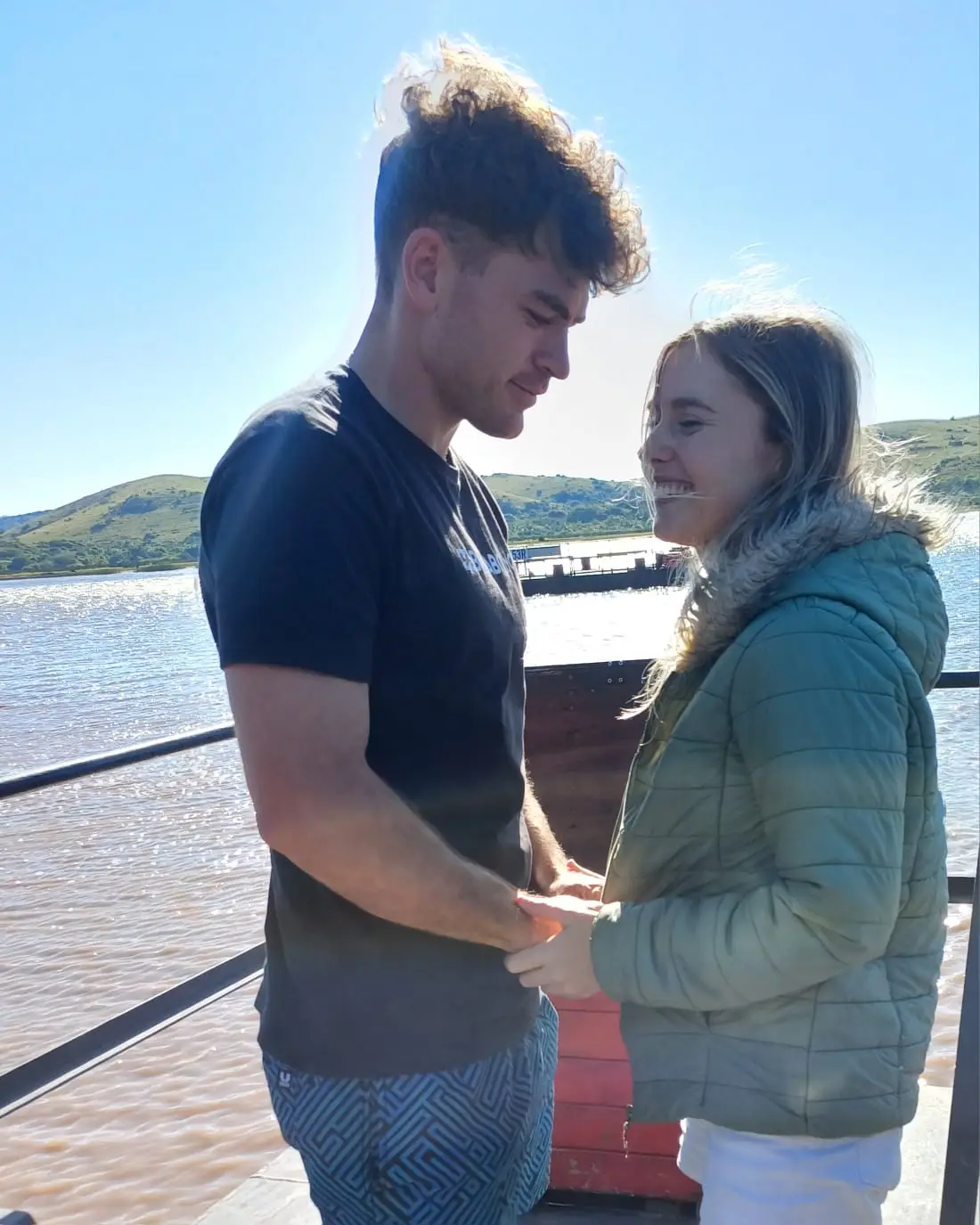 Ockert en Emja hand aan hand by die water op ’n winderige dag.