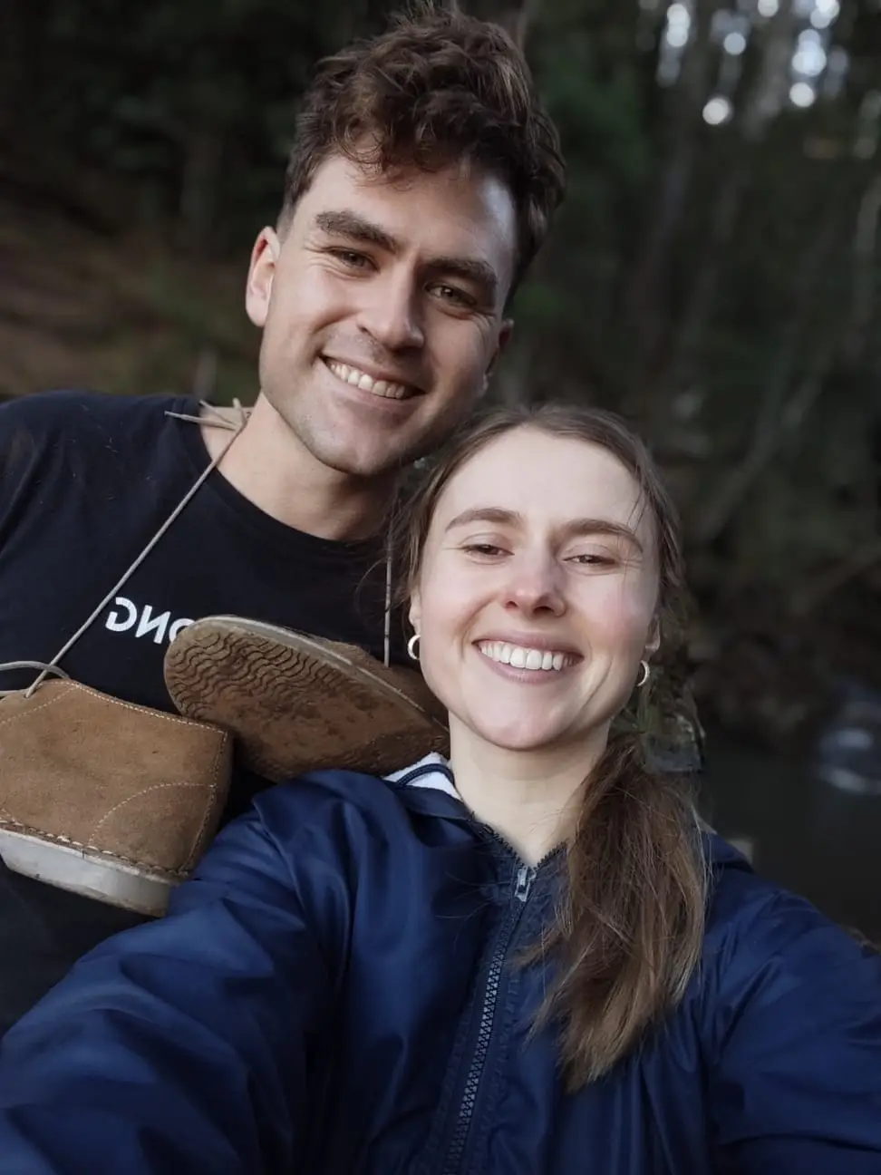 Ockert en Emja langs ’n rivier in die bos, warm aangetrek.